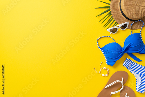 Dream vacation concept. Top view photo of straw hat, blue swimsuit, sunglasses and slippers with shell bracelet on isolated bright yellow background with copyspace