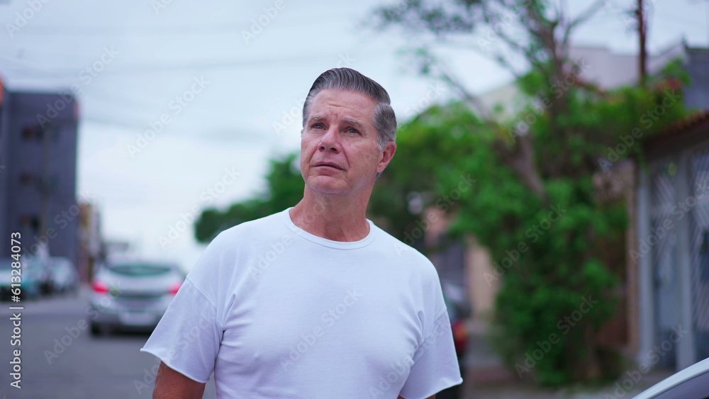 Pensive senior man walking in street in daylight. A middle-age caucasian male strolling in urban environment with thoughtful expression, contemplative emotion Pensive senior man walking in street in daylight. A middle-age caucasian male strolling in urban environment with thoughtful expression, contemplative emotion