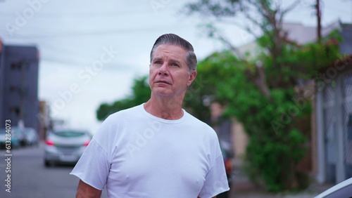 Pensive senior man walking in street in daylight. A middle-age caucasian male strolling in urban environment with thoughtful expression, contemplative emotion