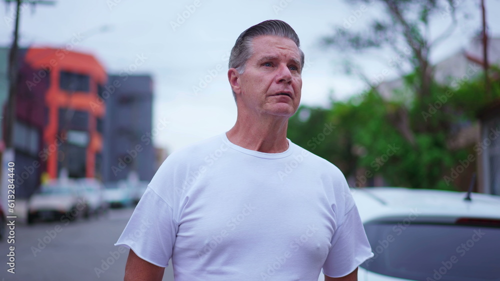 Pensive senior man walking in street in daylight. A middle-age caucasian male strolling in urban environment with thoughtful expression, contemplative emotion Pensive senior man walking in street in daylight. A middle-age caucasian male strolling in urban environment with thoughtful expression, contemplative emotion