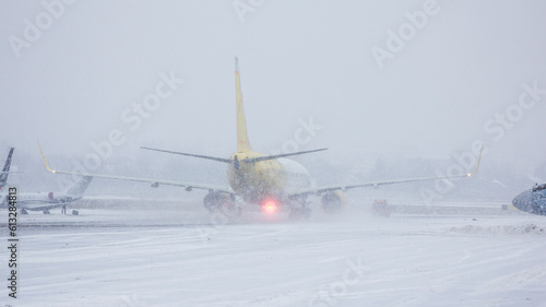 Yellow and white twin-engine passenger plane rides on the taxiway to take off in a heavy snow storm, flying in bad weather, the plane is preparing for takeoff, flying in winter