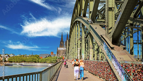 Cologne (Köln), Germany - June 6. 2023: Cycle- and footpath over Hohenzollern rhine bridge to dome cathedral on sunny summer day