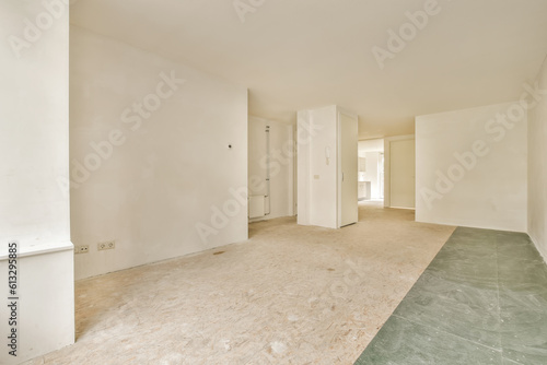 an empty room with white walls and green flooring on the right  there is a door in the middle
