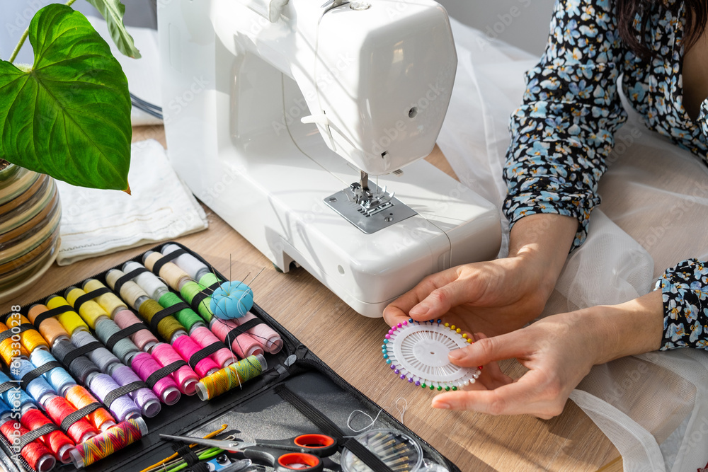 Stockfoto med beskrivningen Woman hand close up sews tulle on electric  sewing machine. Filling the thread into the sewing needle, adjusting the  tension. Comfort in the house, a housewife's hobby, layout of