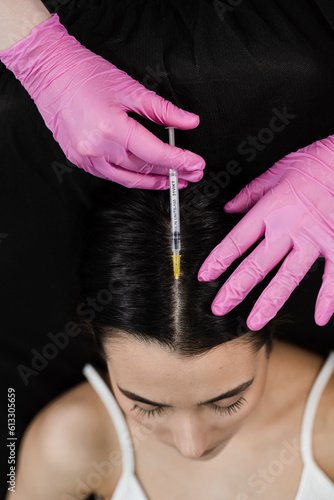 Cosmetologist is making mesotherapy injections in hair of girl top view. Mesotherapy treatment nourish the scalp and boost hair thickness and growth, helping to prevent hair loss.