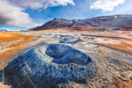 Breathtaking boiling mudpots in geothermal area Hverir and cracked ground around.