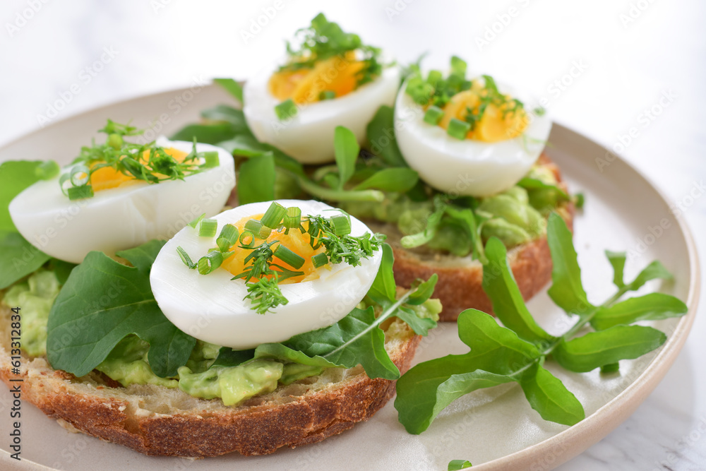Breakfast avocado toast with hard-boiled eggs garnished with herbs