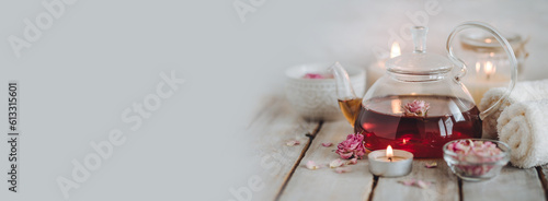 Concept of natural organic flower, herbal ingredients for spa treatment for relaxation and detox. Hot tea with rose extract, petals for beauty procedures, towel, candles. Detention, meditation banner
