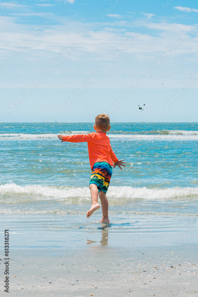 child throwing sand into ocean