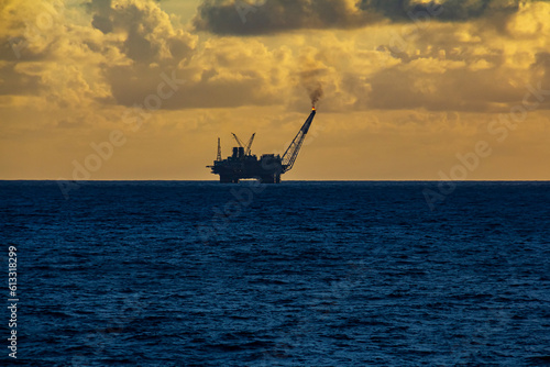 Offshore oil and rig platform in the sunset or sunrise time. Construction of production process in the sea. Power energy of the world.
