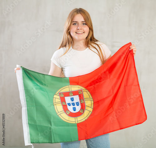 Attractive smiling female football fan holding Portugal flag