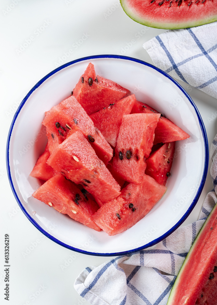 Sliced fresh watermelon on an enamel plate on a white background. Top close view of a plate of watermelon chunks. Sliced fresh watermelon on an enamel plate on a white background. Top close view of a plate of watermelon chunks.