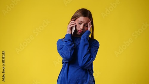 4k video of one sadly girl who talking to someone on the phone over yellow background.