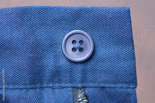 one blue plastic button on the fabric of the jacket sleeve on a brown background photo