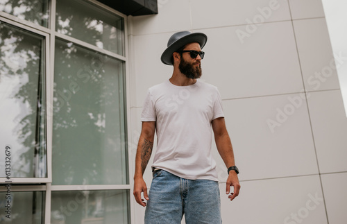 City portrait of handsome hipster guy with beard wearing white blank t-shirt. Mock-up for print. T-shirt template.