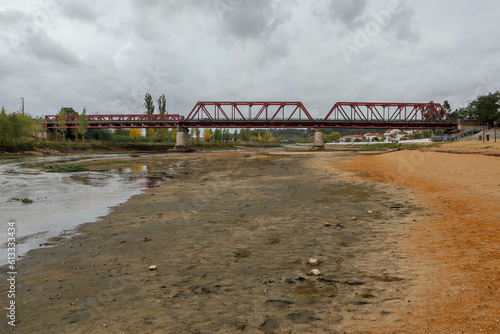 Drought in Sorraia river with Red Iron Bridge in background at Coruche, Santarem, Portugal photo