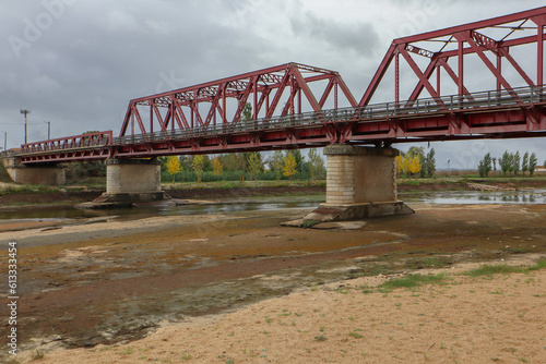 Drought in Sorraia river with Red Iron Bridge in background at Coruche, Santarem, Portugal