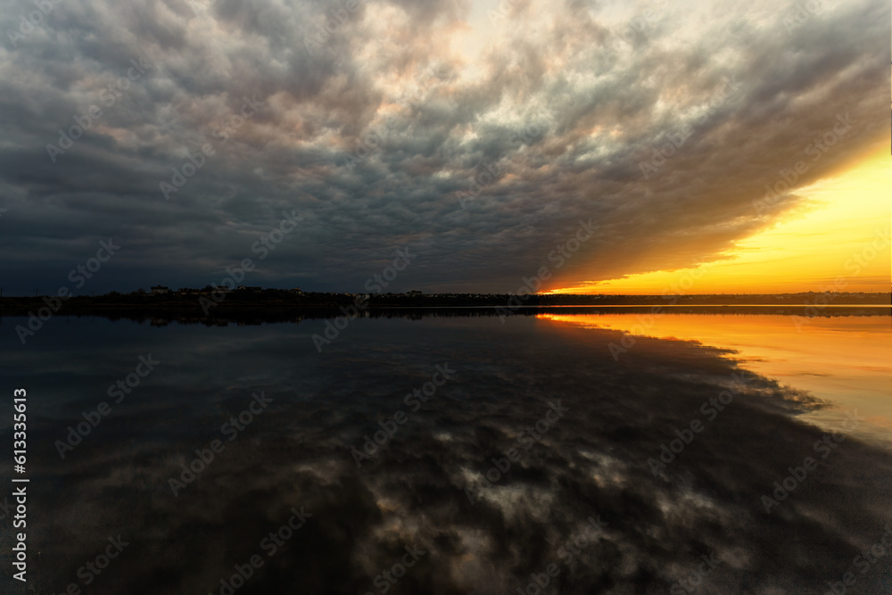 Warm sunset over a lake with dramatic clouds after a thunderstorm