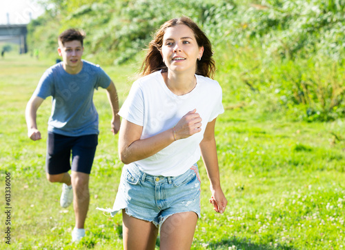 Fototapeta Naklejka Na Ścianę i Meble -  Cheerful teenagers are jogging together in the park and having fun