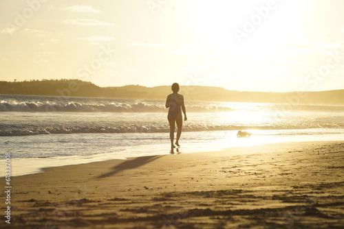 Mujer caminando sola al atardecer junto al mar photo