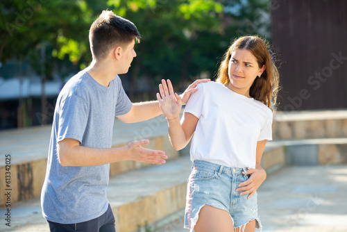 Guy is bothering young lady in the park and she's rejecting him photo