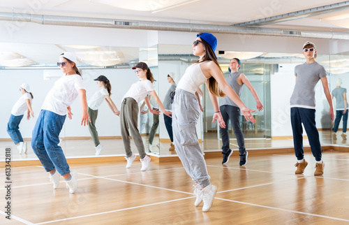 Happy smiling teenagers practicing vigorous hip hop movements in dance class