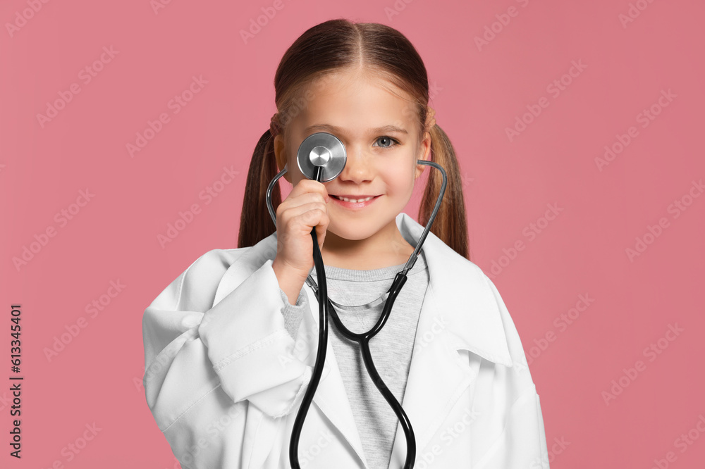 Little girl in medical uniform with stethoscope on pink background Little girl in medical uniform with stethoscope on pink background