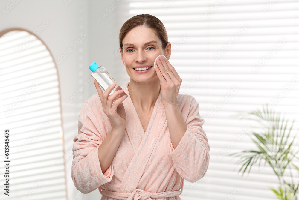 Beautiful woman removing makeup with cotton pad indoors Beautiful woman removing makeup with cotton pad indoors