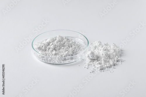 Petri dish and calcium carbonate powder on white background