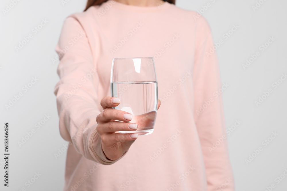 Healthy habit. Closeup of woman holding glass with fresh water on light grey background Healthy habit. Closeup of woman holding glass with fresh water on light grey background