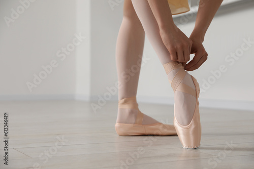 Ballerina tying pointe shoes in dance studio, closeup. Space for text © New Africa