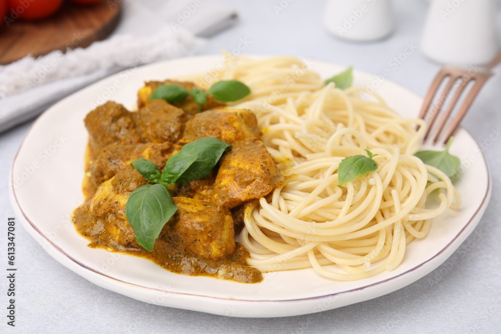 Delicious chicken, pasta with curry sauce and basil served on white table, closeup