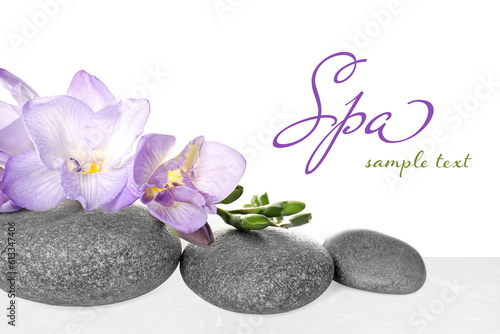 Spa stones and freesia on light marble table against white background, closeup. Design with space for text