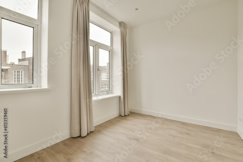 an empty room with wood flooring and large windows in the wall is white  there is a window that looks out to the