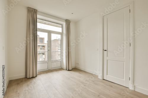 an empty room with wooden floors and white walls, there is a door leading to the right side of the room