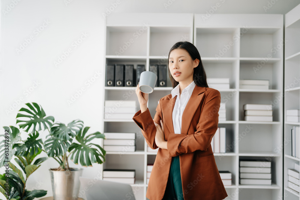 Young attractive Asian female office worker business suits smiling at camera in modern office . Young attractive Asian female office worker business suits smiling at camera in modern office .