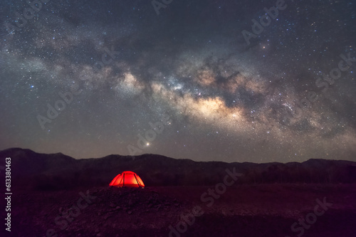 Red tent in reservoir under Milky way galaxy with stars and space dust in the universe, long speed exposure with noise. Baan Sop pat, Mae Moh Lampang Thailand.