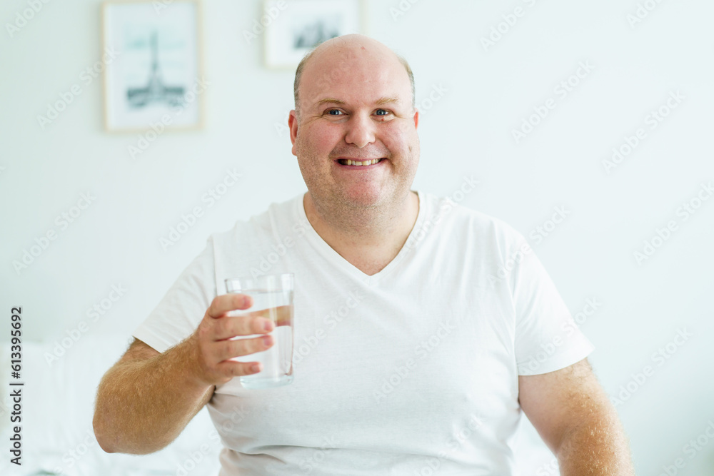 Caucasian white fat man drinks a water in a drinking glass in every morning. Caucasian white fat man drinks a water in a drinking glass in every morning.