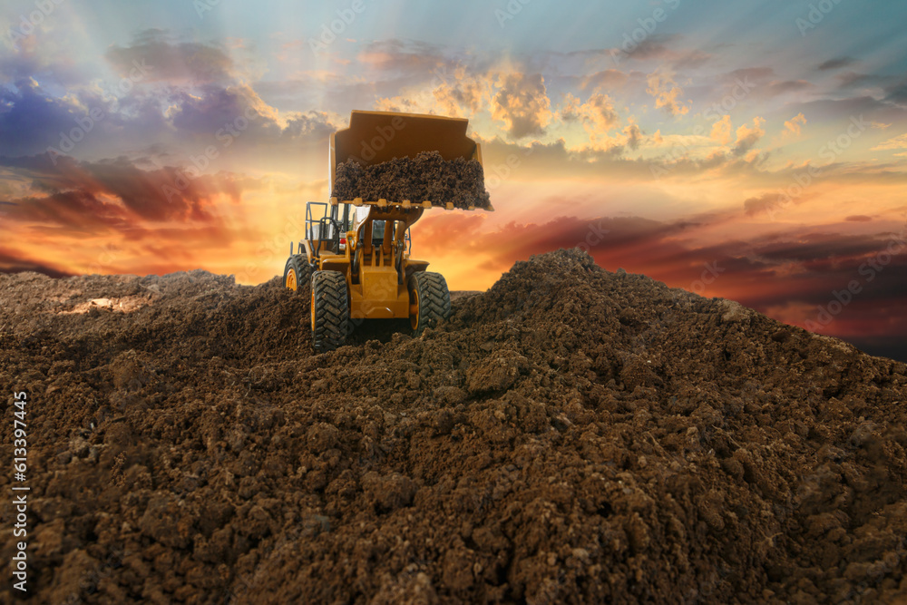 Wheel loader are digging the soil in construction site on sunset background,with bucket lift up Wheel loader are digging the soil in construction site on sunset background,with bucket lift up
