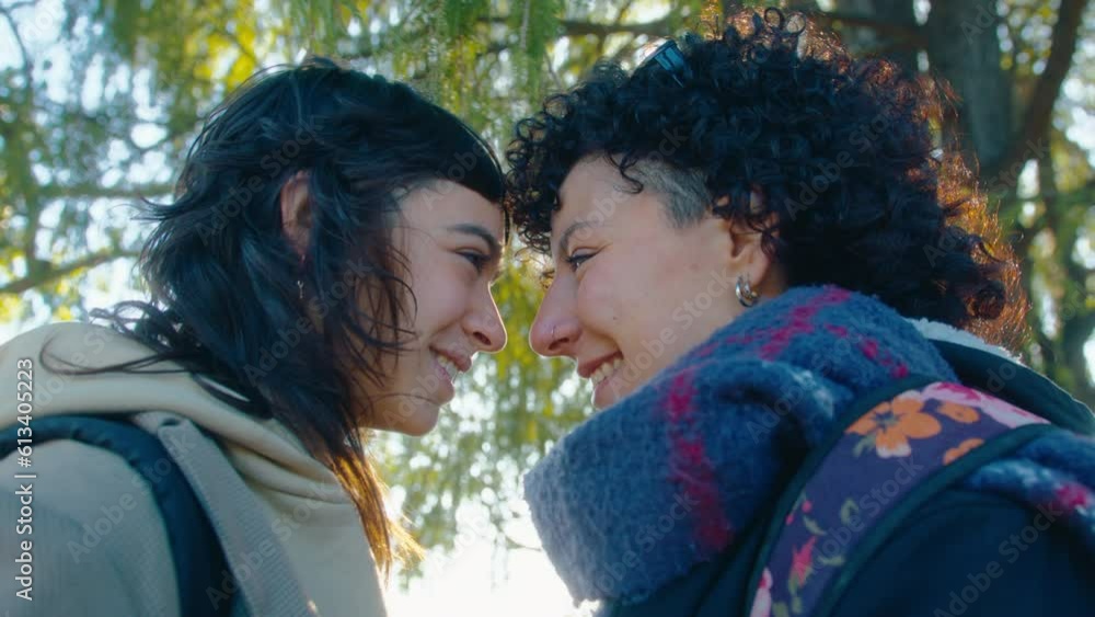 Young happy lesbian couple in love touching foreheads, smiling and talking, having romantic date outdoors on sunny day. Handheld camera shot Young happy lesbian couple in love touching foreheads, smiling and talking, having romantic date outdoors on sunny day. Handheld camera shot