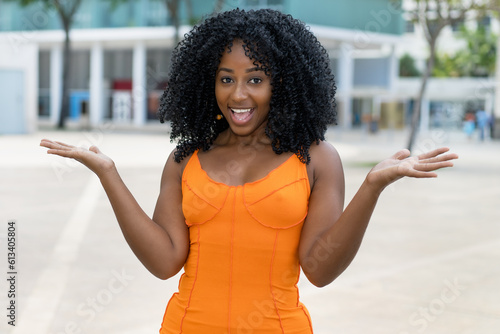 Excited brazilian woman with orange dress outdoors in summer