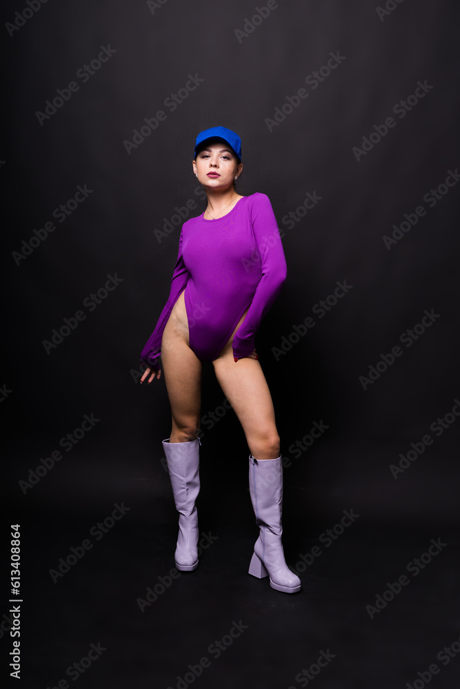 Attractive and slender brunette girl in violet bodysuit underwear in studio. Body care concept.