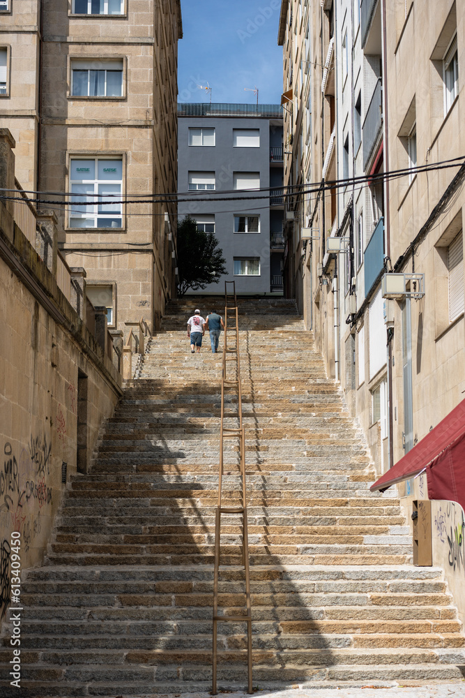 long staircases between urban buildings with a couple of people walking up them 