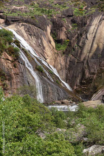 vertical image of the tree-filled mountain waterfall in the foreground of the   zaro in Dumbria  La Coru  a  Galicia  Spain