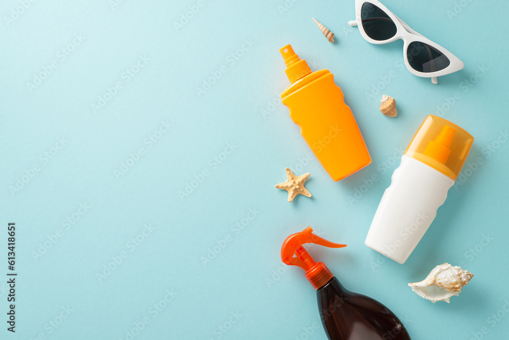 Sun protection collection. Blank space for branding on a pastel blue background featuring top view of sunblock oil and SPF cream bottles without labels, sunglasses, shells, and starfish Sun protection collection. Blank space for branding on a pastel blue background featuring top view of sunblock oil and SPF cream bottles without labels, sunglasses, shells, and starfish
