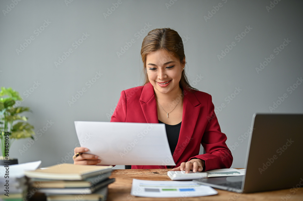 An Asian businesswoman using a calculator to plan budgets and working on financial reports An Asian businesswoman using a calculator to plan budgets and working on financial reports