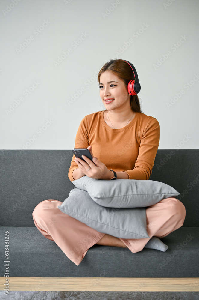 A woman listening to music through her headphones while relaxing in her living room