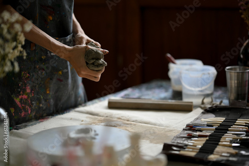 Close-up image of a master clay artist or potter kneading raw clay at his desk