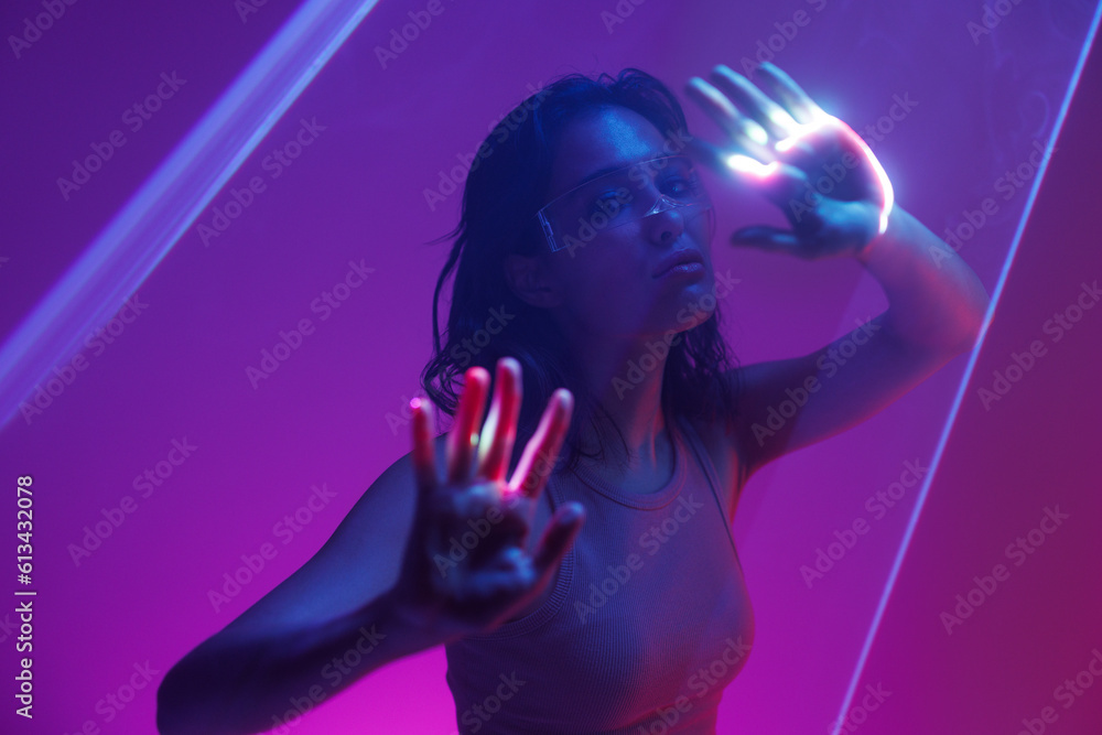 Hologram woman in futuristic costume with flowing hair. Female in modern VR glasses interacting with network while having virtual reality experience. Augmented reality game, future technology, AI. Hologram woman in futuristic costume with flowing hair. Female in modern VR glasses interacting with network while having virtual reality experience. Augmented reality game, future technology, AI.