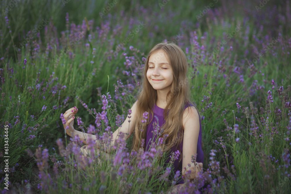 Young cute smiling girl teen in violet dress sitting in lavender field among flowers in Provence at sunset, relaxing and meditating, outdoor lifestyle, idea of rest, summer vibe, beauty and happiness Young cute smiling girl teen in violet dress sitting in lavender field among flowers in Provence at sunset, relaxing and meditating, outdoor lifestyle, idea of rest, summer vibe, beauty and happiness